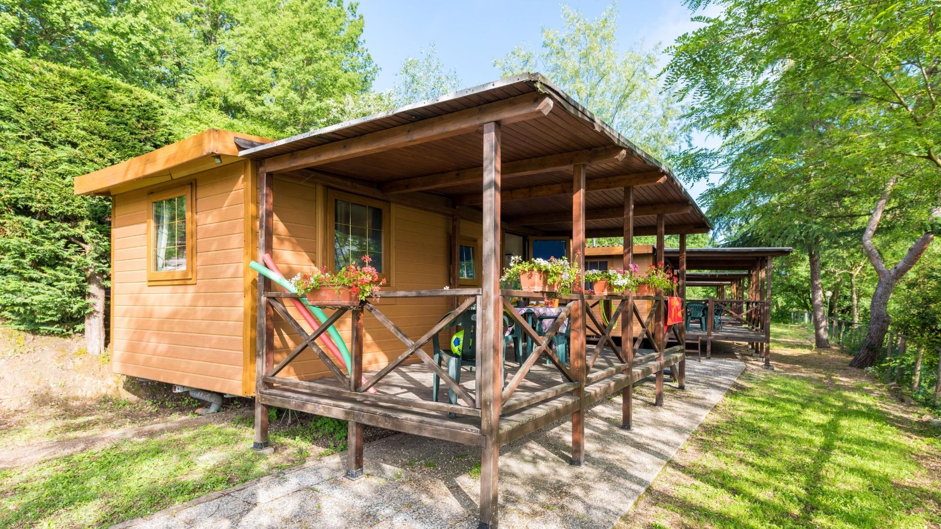 Casetta di legno immersa nel verde, con veranda fiorita e atmosfera rilassante.