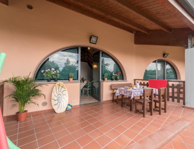 Terrazza accogliente, tavolo apparecchiato, fiori, sole, atmosfera rilassante e calda.