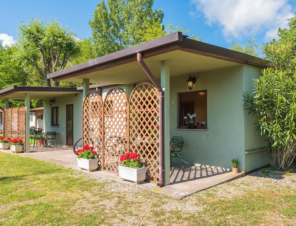 Case mobili immerse nel verde, sole splendente, atmosfera rilassante e natura rigogliosa.